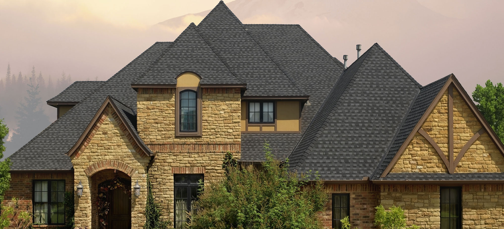Large brick and stone home with a black shingle roof